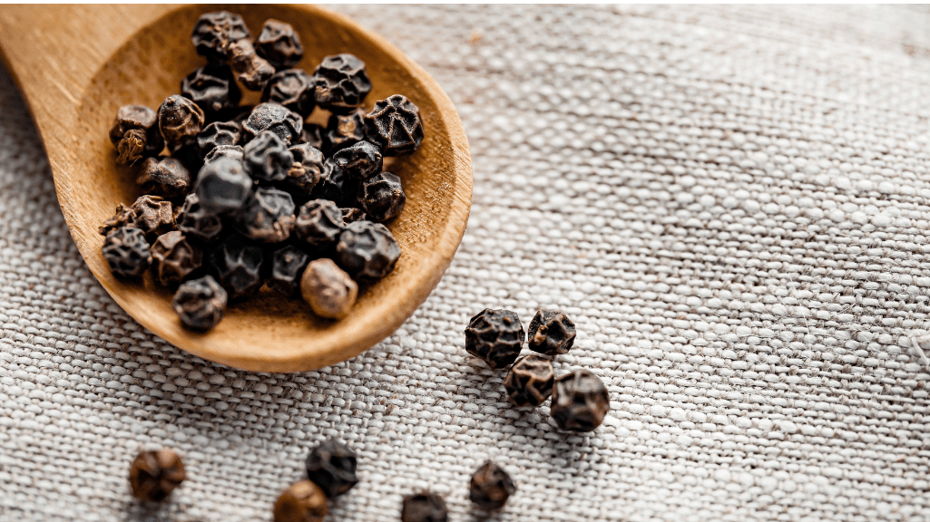 Black pepper on a wooden spoon.