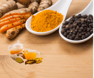 turmeric and black pepper in a spoon kept on table.